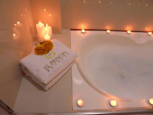 een badkamer met een bad, kaarsen en een handdoek bij El Principe Hoteles in Piura