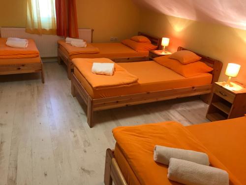 a room with four beds with orange sheets at Tó- Party Panoráma Panzió & Wellness in Kiszombor