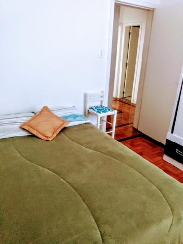 a bedroom with a green blanket on a bed at Próximo ao Consulado - Quarto Inteiro in Porto Alegre