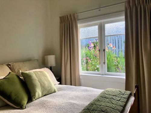 ワイヒにあるAraluen Cottageのベッドルーム1室(ベッド1台付)、花の咲く窓が備わります。