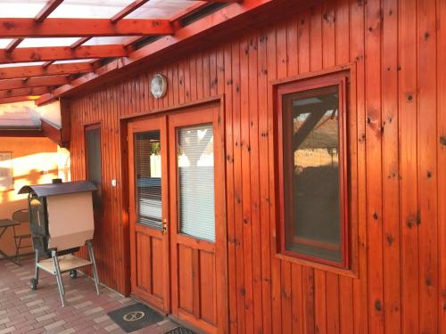 a wooden cabin with a window and a chair at Tó- Party Panoráma Panzió & Wellness in Kiszombor