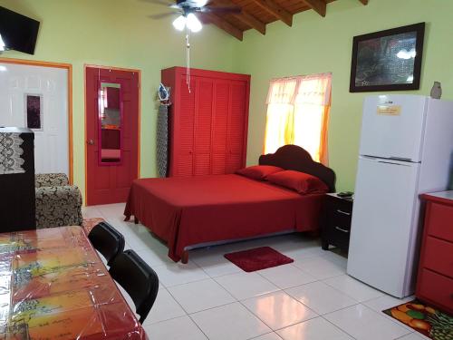 a bedroom with a red bed and a refrigerator at Tequila Sunrise Antigua in Osbourn