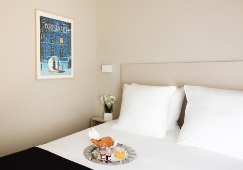 a plate of food on a bed with two pillows at Hôtel Helzear Etoile in Paris