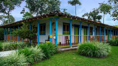 a small house with blue and yellow trim in a yard at Finca Hotel los Nogales in Quimbaya