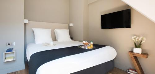 a hotel room with a large bed and a tv at Hôtel Helzear Etoile in Paris