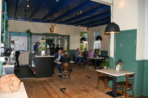 B&B Herberg Foestrum في Westergeest: مجموعة من الناس يجلسون على الطاولات في المطعم