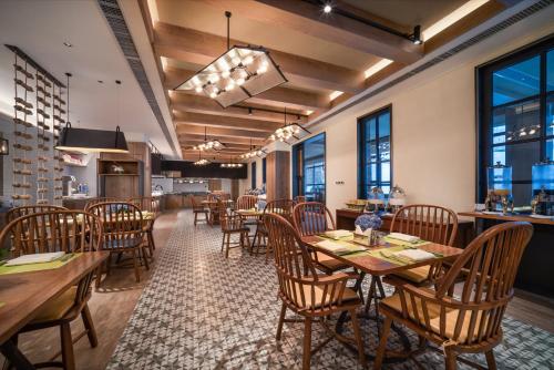 a restaurant with wooden tables and chairs and windows at Holiday Inn Jilin Beidahu, an IHG Hotel in Jilin