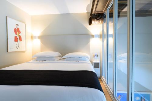 a bedroom with a bed with white sheets and pillows at Hôtel Helzear Etoile in Paris
