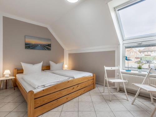 a bedroom with a bed and two chairs and a window at Cozy Apartment in Insel Poel near Beach in Oertzenhof