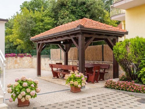 a wooden gazebo with a picnic table and benches at Alluring Apartment in Imotski with Parking in Imotski