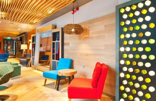 a lobby with a red chair and blue chairs at Holiday Inn Tampere - Central Station by IHG in Tampere