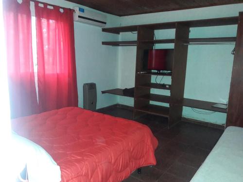 Schlafzimmer mit einem roten Bett und einem TV in der Unterkunft Cabañas El Mirador de Icho Cruz in Villa Icho Cruz