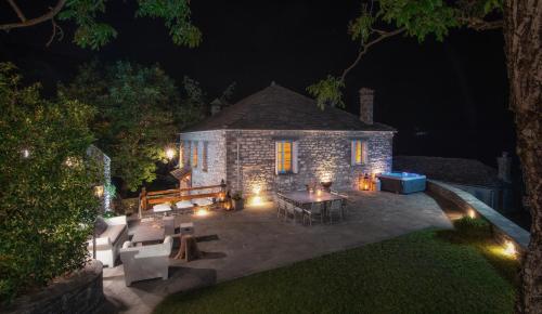 a stone house with a patio at night at 5 Senses in Dikoryfo