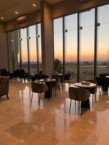 a restaurant with tables and chairs and large windows at قولدن سكوير طريق الرياض Golden Square Riyadh Road in Khamis Mushayt