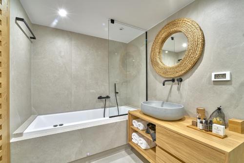 a bathroom with a sink and a tub and a mirror at Vista Del Porto Luxury Suites in Rethymno Town