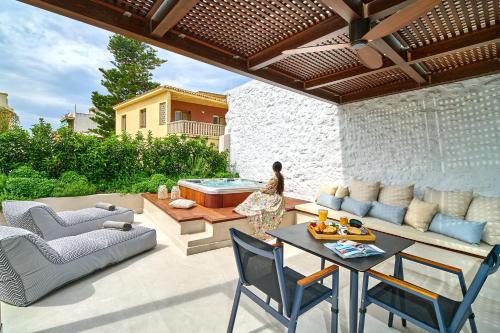 a patio with a table and chairs and a hot tub at Vista Del Porto Luxury Suites in Rethymno Town