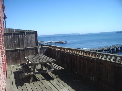 a wooden bench sitting on a boardwalk next to the ocean at The Monarch Hotel in Port Townsend