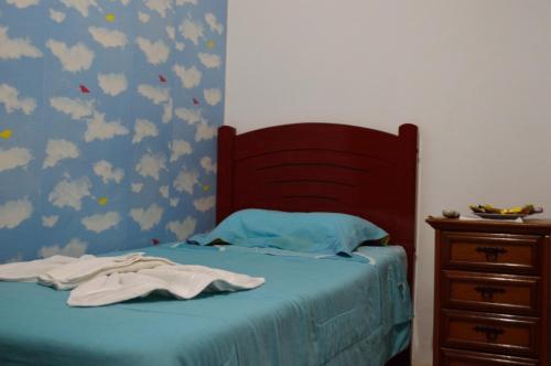 a bed with a blue blanket and a dresser at Pousada e Restaurante Tio Paulo in Teresópolis