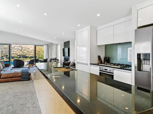 a kitchen with white cabinets and a living room at Highview Haven by Relaxaway Holiday Homes in Queenstown
