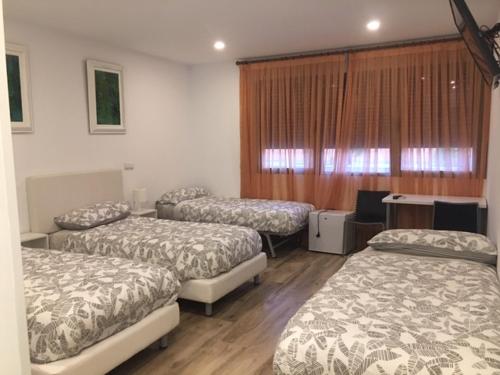 three beds in a room with wooden floors at Rooms H Skyline in Alcorcón