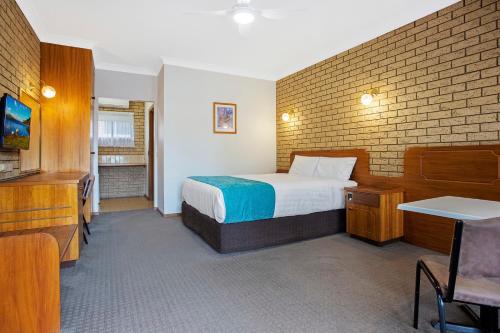a hotel room with a bed and a brick wall at Manifold Motor Inn in Camperdown