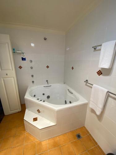 a white bathroom with a tub and a shower at Taree Motor Inn in Taree