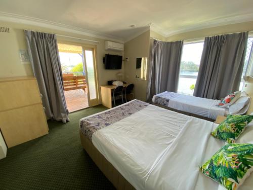 a hotel room with two beds and a balcony at Taree Motor Inn in Taree