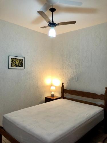 a bedroom with a bed with a ceiling fan at Chalé Pura Vida - Casa de madeira no centro in São Roque de Minas