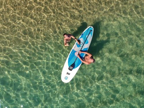 deux hommes debout sur une planche de surf dans l'eau dans l'établissement Mar da Lua, à Praia de Araçatiba