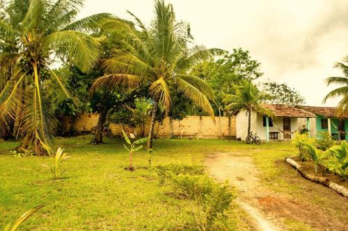 una casa con palmeras y un camino de tierra en Hospedaria Caribe en Cumuruxatiba