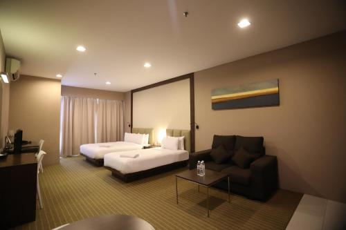 um quarto de hotel com uma cama e um sofá em Hotel Primera Suite - formally known as Tan Yaa Hotel Cyberjaya em Cyberjaya