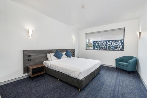 梅特兰Thornton Executive Hotel的一间带床和蓝色椅子的酒店房间