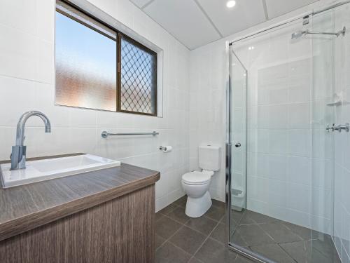 a bathroom with a toilet, sink, and shower at Chalet Motor Inn in Bundaberg