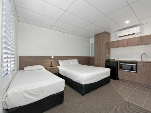 a hotel room with two beds and a kitchen at Chalet Motor Inn in Bundaberg