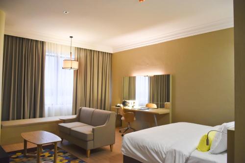 a hotel room with a bed and a chair and a desk at UCSI Hotel Kuching in Kuching