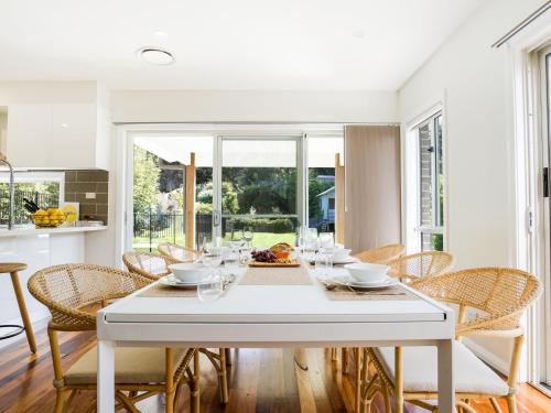 a white dining room with a white table and chairs at Blissful Bungalow in Culburra Beach