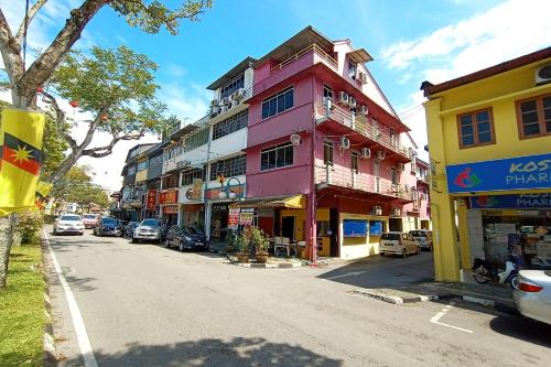 een roze gebouw aan de kant van een straat bij SPOT ON 90119 Bed's Guesthouse in Kuching