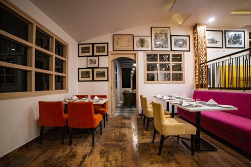a restaurant with tables and chairs and a pink couch at juSTa Mukteshwar Retreat & Spa in Mukteswar