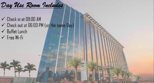 a large glass building with palm trees in front of it at Howard Johnson By Wyndham, Hebbal, Bengaluru in Bangalore