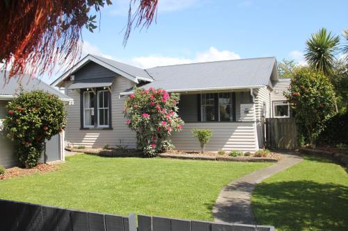 a white house with flowers in the yard at Linton Cottage in Palmerston North