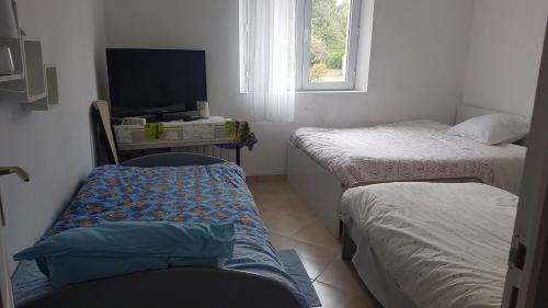 a room with two beds and a desk with a television at SUPER SPACIEUX GÎTE PROCHE DE TOUTES COMMODITÉS in Saint-Just-Sauvage