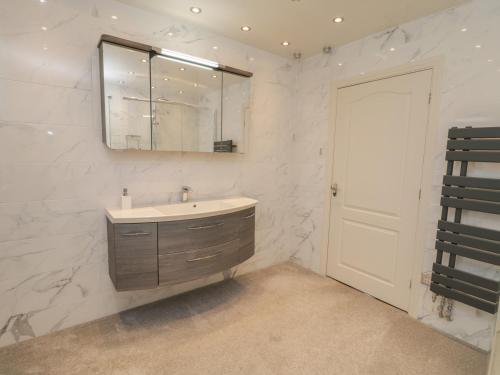 a white bathroom with a sink and a mirror at Holly Edge in Saltburn-by-the-Sea