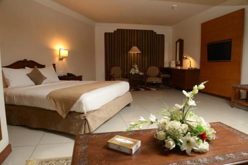 um quarto de hotel com uma cama e uma mesa com flores em Regent Plaza Hotel & Convention Center em Carachi