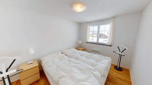 a white bed in a room with a window at Am Bachji in Belalp