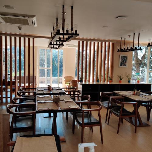 a dining room with tables and chairs and windows at Yog Wellness Resort & Spa By Amritara in Mussoorie