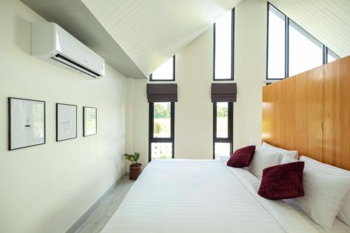 una camera da letto con un grande letto bianco con cuscini rossi di Baan Ga-Cha a Chiang Rai