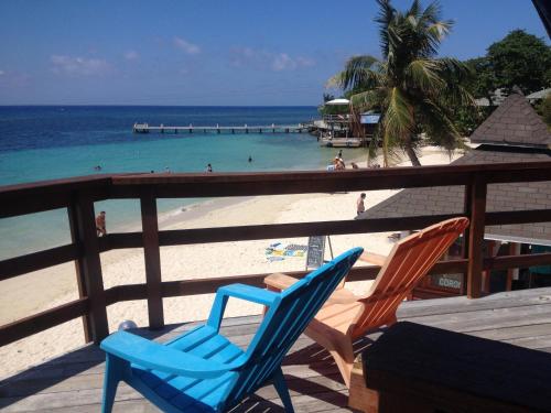 two blue chairs sitting on a deck near the beach at Fosters West Bay Resort in West Bay