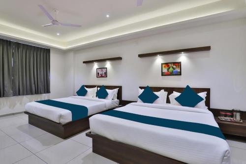 a bedroom with two beds with blue and white sheets at Hotel Sparsh Inn - Chandkheda in Ahmedabad