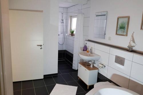 a white bathroom with a sink and a toilet at Idyllische Ferienwohnung zum Wohlfühlen+Entspannen in Lichtenstein