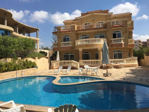 a resort with a swimming pool in front of a building at North Coast Villa sea view with private pool in Alexandria